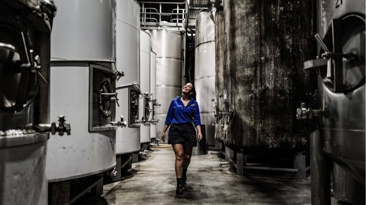 Female winemaker Kate Sturgess walking through Brokenwood barrel room